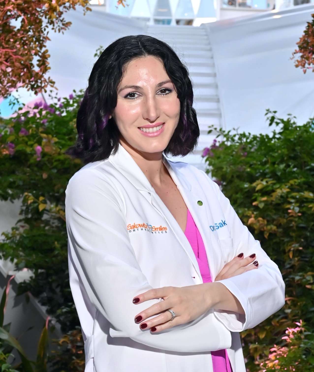 Dr. Marla Sakowitz, orthodontist at Sakowitz Smiles, smiling in her white coat with arms crossed