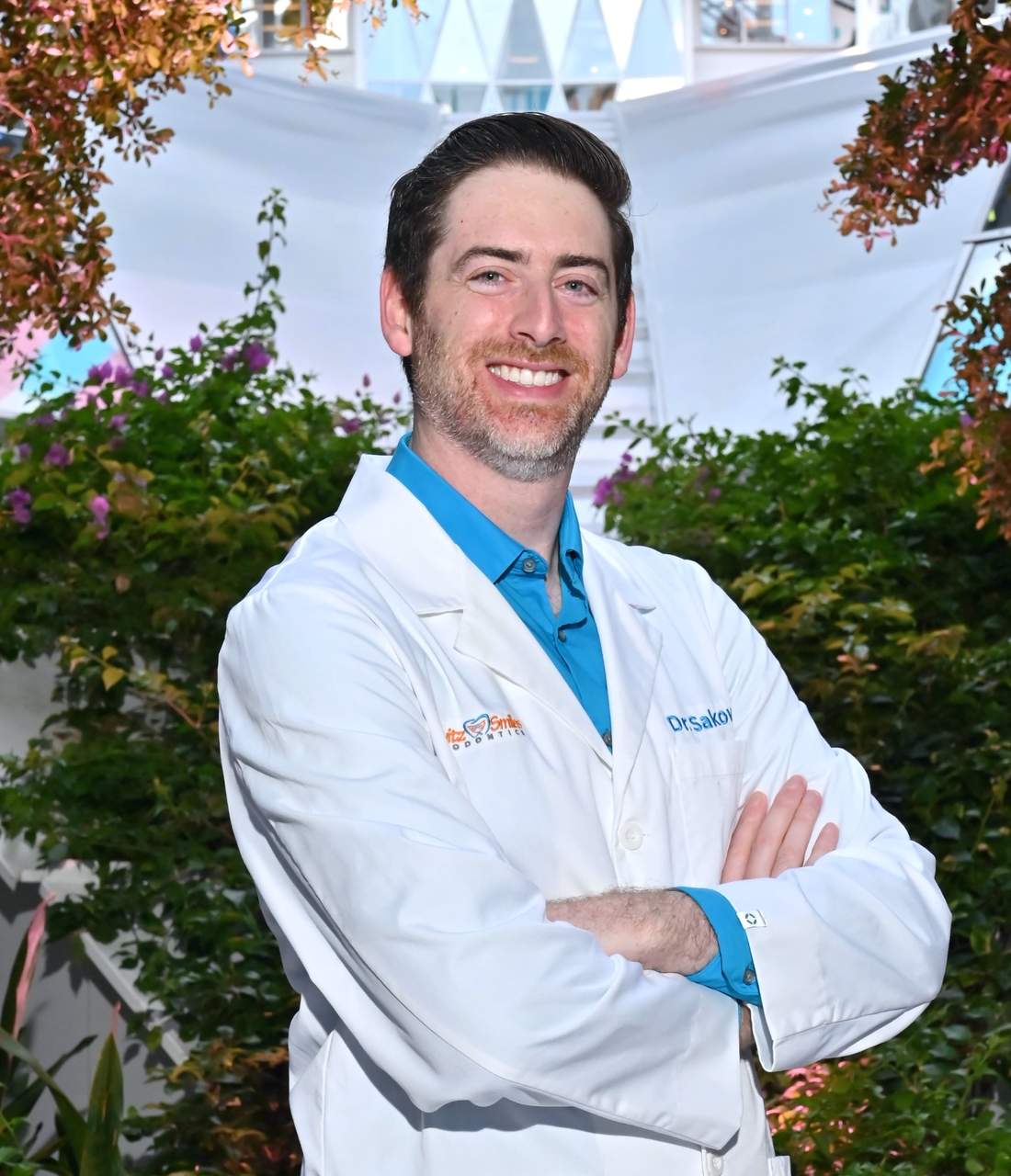 Dr. Scott Sakowitz, orthodontist at Sakowitz Smiles, smiling in his white coat with arms crossed