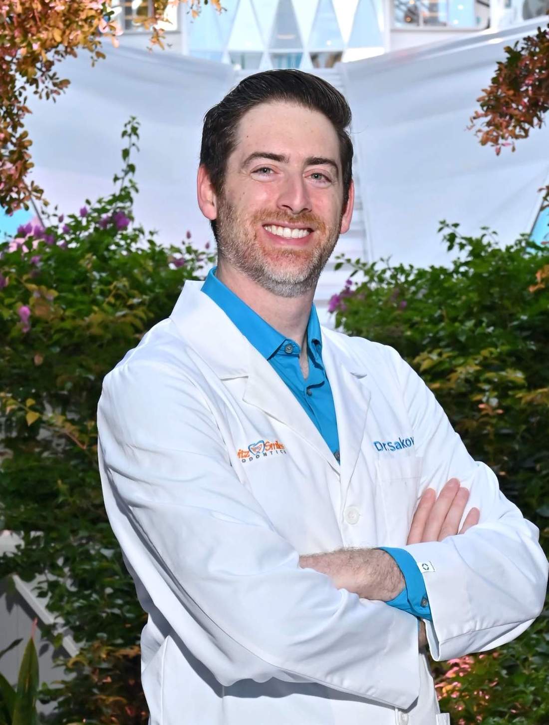 Dr. Scott Sakowitz, orthodontist at Sakowitz Smiles, smiling in his white coat with arms crossed