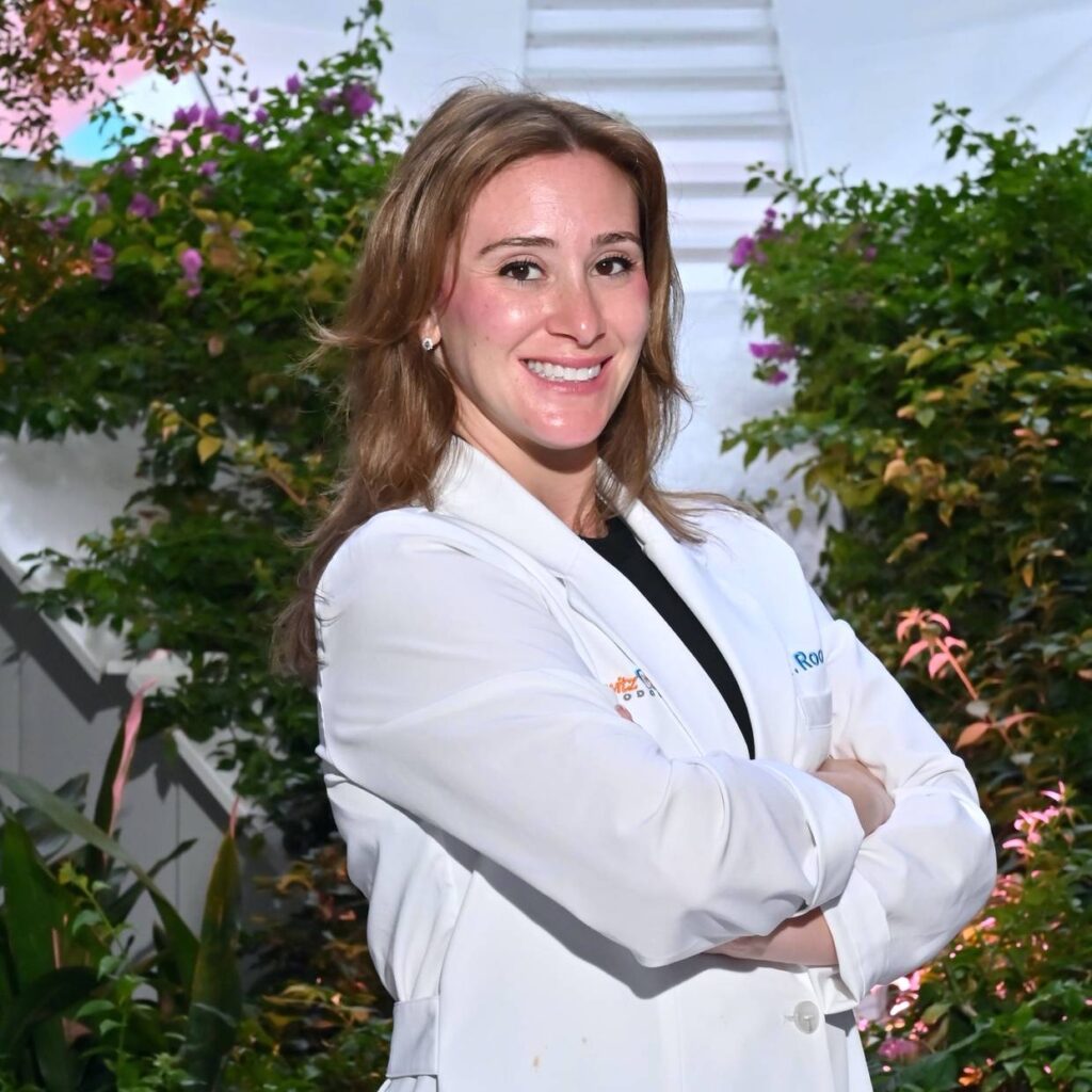 Dr. Shannon Rooney, orthodontist at Sakowitz Smiles, smiling in her white coat with arms crossed